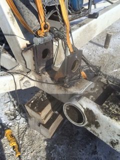 Frame repair in progress on heavy equipment, with lifting chains and welded brackets